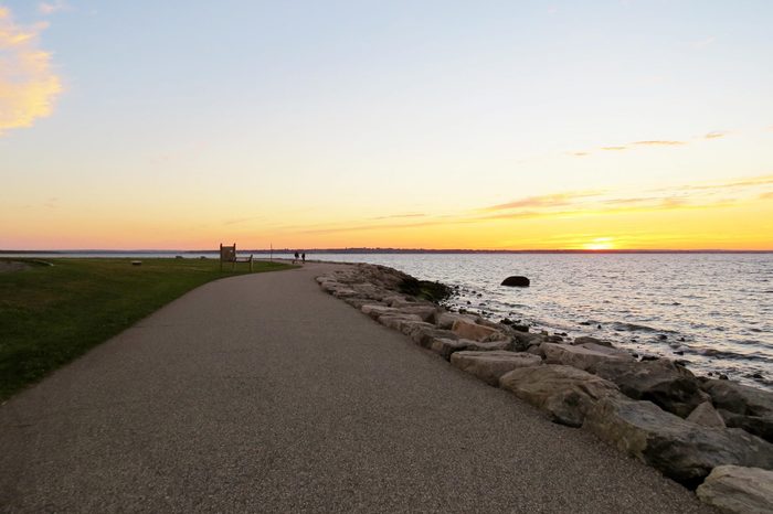 A tranquil path along a rocky seashore at sunset; Colt State Park, Rhode Island