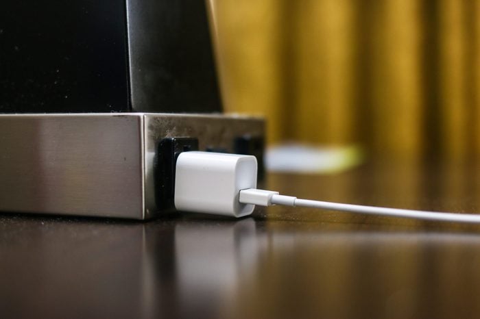 An iPhone charger is plugged into a lamp in a hotel room