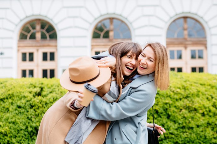 Two laughing candide hipster blond women in trendy clothes. Female posing on street background. Female showing positive face emotions. Lifestyle concept.