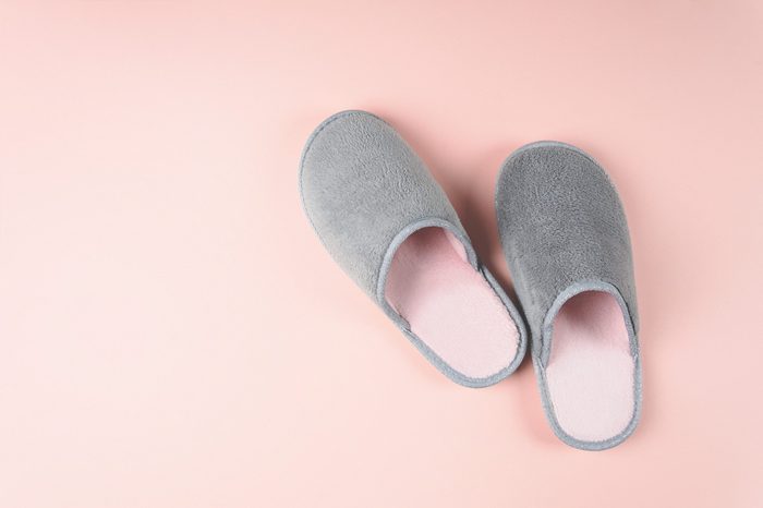 Gray and pink home slippers on a pastel paper background. Top view. Copy space. Toned