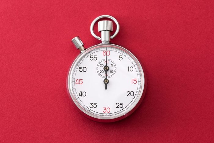 Analogue metal stopwatch on the red background.