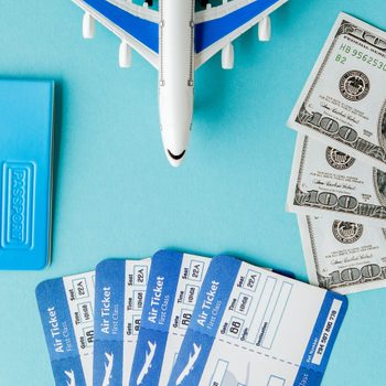 Passport, dollars, plane and air ticket on a blue background. Travel concept, copy space.