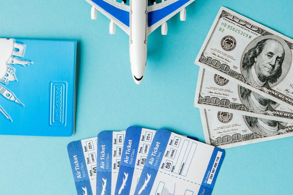 Passport, dollars, plane and air ticket on a blue background. Travel concept, copy space.