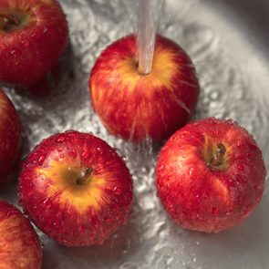 Close-up Washing red apples in a stainless steel kitchen sink.