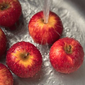 Close-up Washing red apples in a stainless steel kitchen sink.