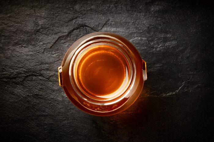 A photo of a vibrant jar of organic honey, shot from above on a black background with copy space