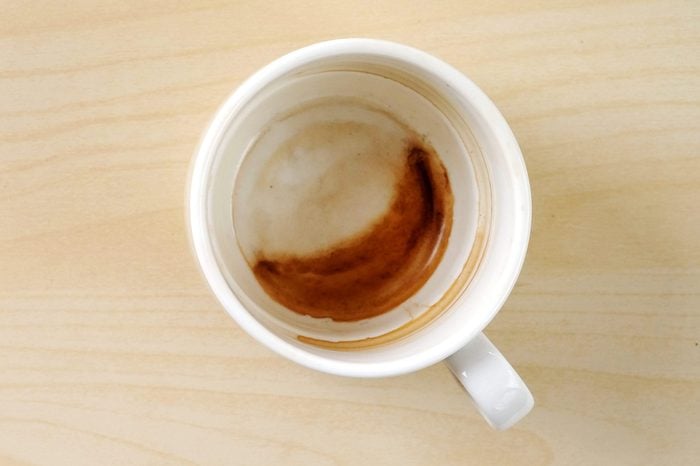 Coffee stain in cup on wood background, with copy space