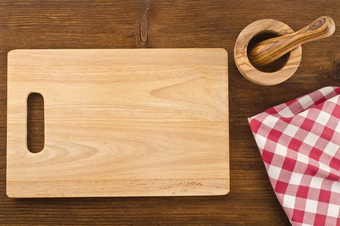 Cutting board with towel and bowl on wooden background 