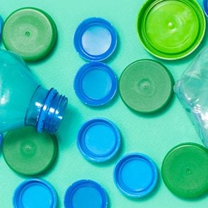 blue and green plastic bottle caps and a plastic water bottle on a green background