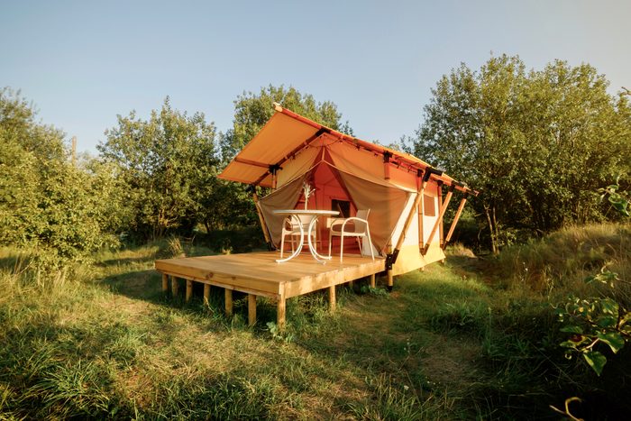 Cozy open glamping tent with light inside during sunset. Luxury camping