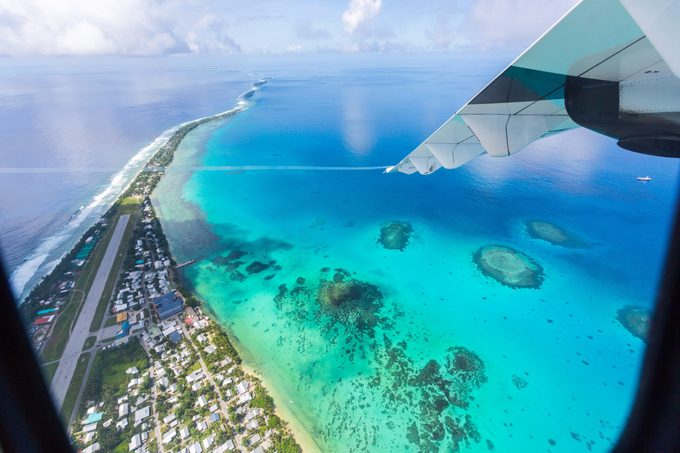 Tuvalu under the wing of the airplane. Aerial view of Funafuti atoll and airstrip of international airport in Vaiaku from air. Fongafale motu. Island nation in Polynesia, South Pacific Ocean, Oceania