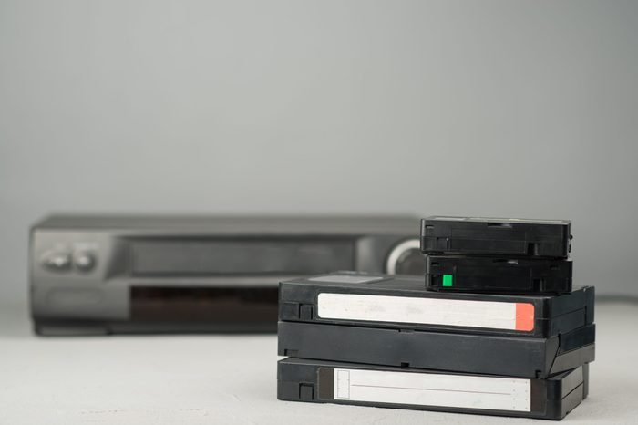Several VHS videotapes on a blue background and video player