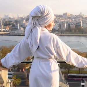 Woman in bathrobe on the terrace of a house at sunrise