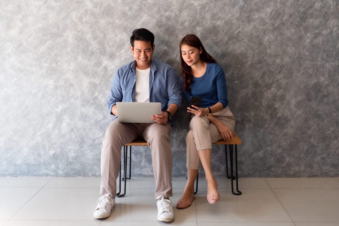 Asian couple man and woman using laptop computer wall background with copy space