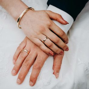Couples Hands With Wedding Rings with wedding dress lace background