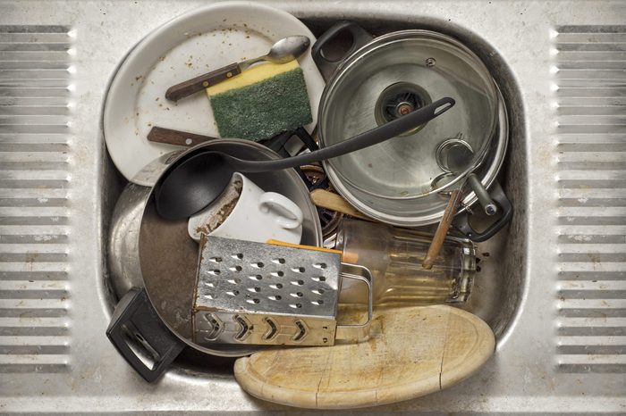Dirty dishes, utensils in the metal sink background
