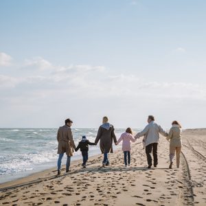 back view of big multigenerational family walking together on seashore