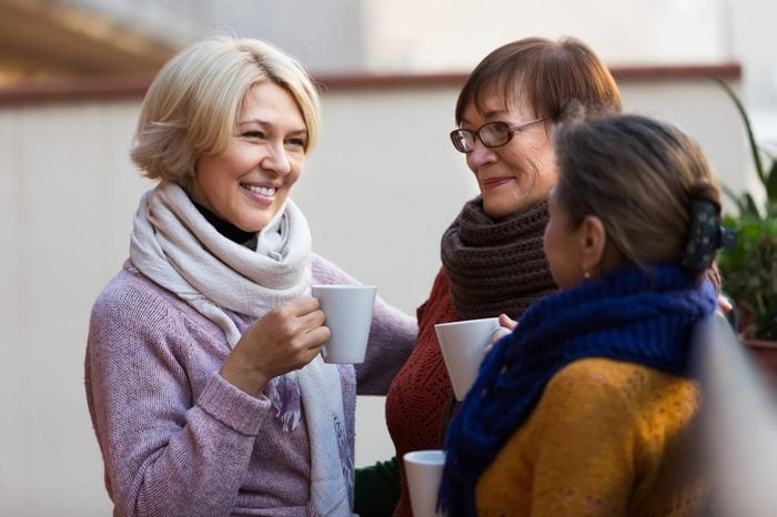 Group of smiling mature women drinking tea at balcony