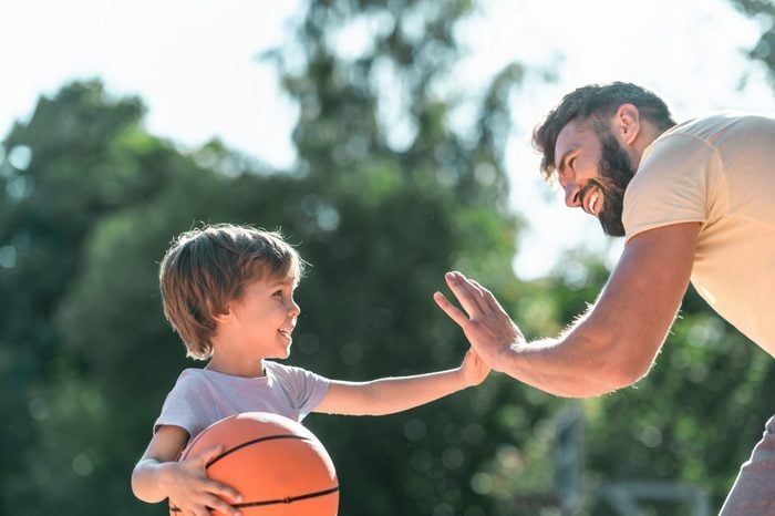 Happy boy and dad with a ball on the basketball court