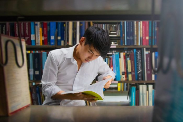 Man reading book at University library . Asian University. Asian library. Man reading book with light fare