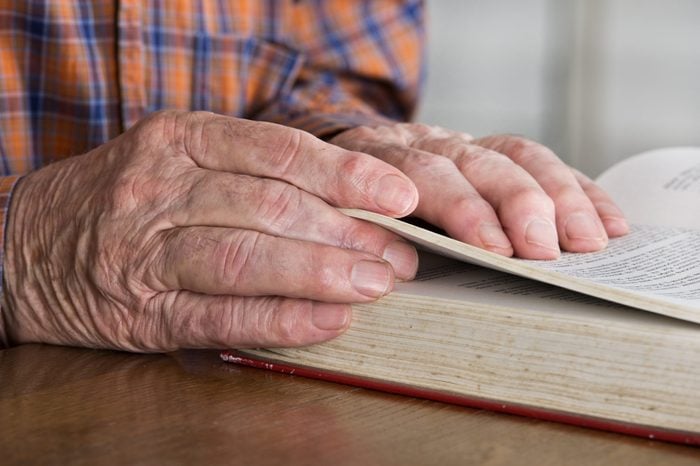 Close up of old man's hands who's reading book