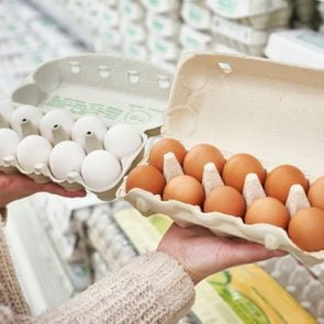 Woman with cardboard packages of white and brown eggs in the store