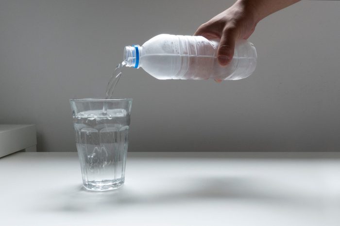 Image picture pouring plastic bottle of water into glass glass