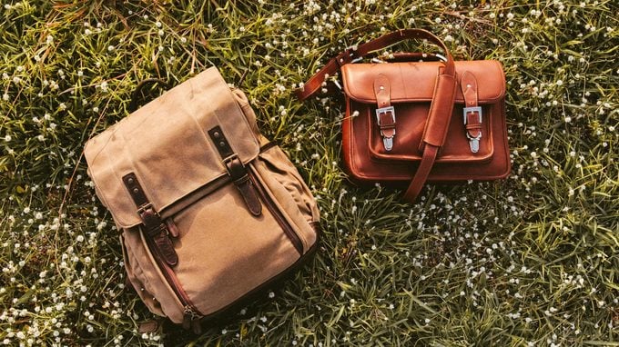 Fine Quality Handmade Leather Messenger Camera Bag and Backpack Flat Lay on Grass