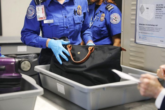 a tsa agent searches a bag at an airport security checkpoint