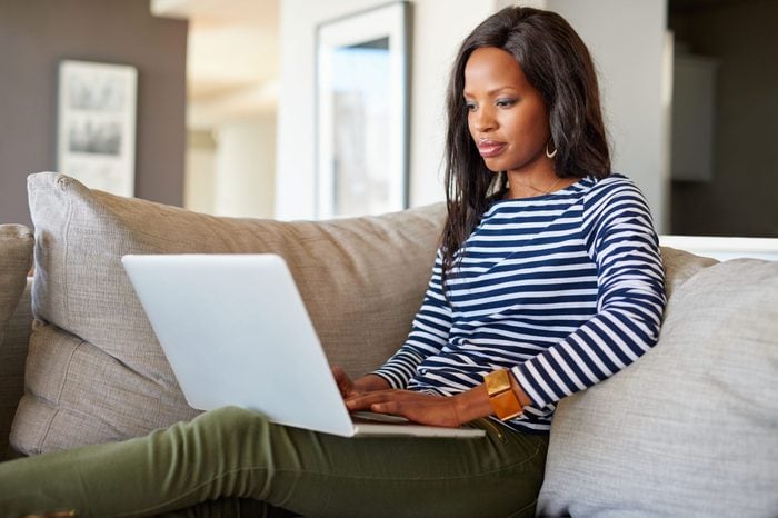 Attractive young woman using a laptop while relaxing on a sofa at home