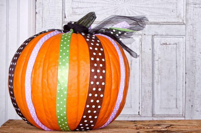 A pumpkin decorated with ribbon with aged door panel for background