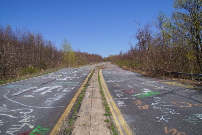Abandoned road of Centralia covered with chalk graffiti in a bright sunny spring day.