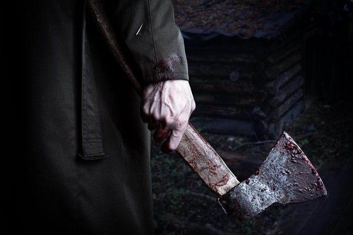Axe with blood in male hand. murderer or butcher, halloween theme