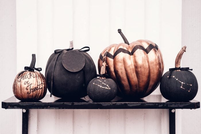 Black and rose cold colored pumpkins against white wall. Copy space