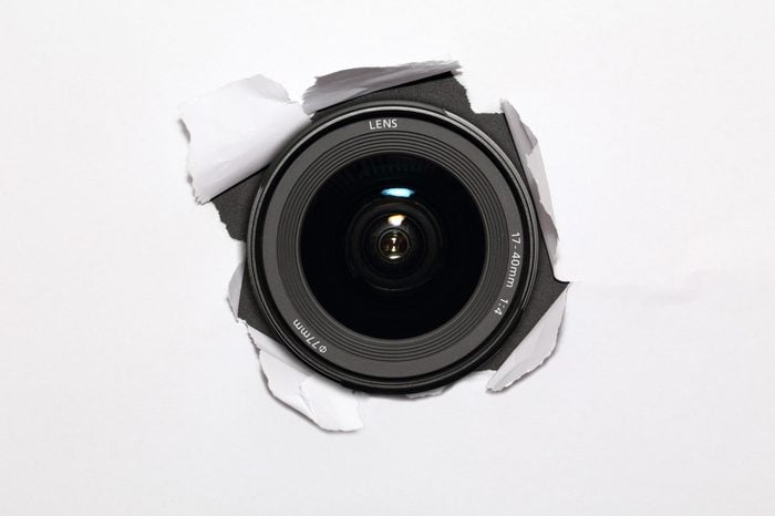 Camera lens hiding behind the paper wall, ready to take a snapsho