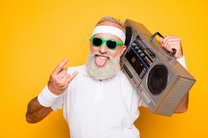 Cheerful excited aged funny active sexy athlete cool pensioner grandpa in eyewear with bass clipping ghetto blaster recorder. Old school, swag, sticking tongue, fooling, gym, workout, technology
