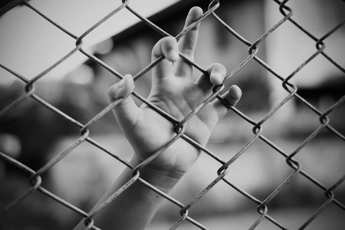Hand in jail with girl and house of detention concept, vignette effect and selective focus, black and white tone.