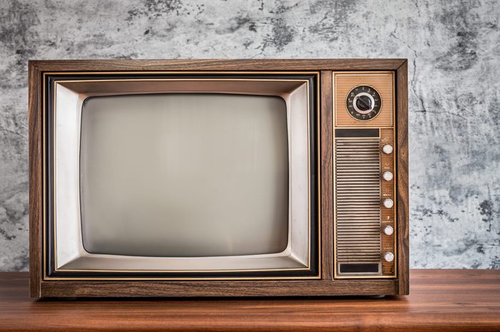 Old television on wooden table with concrete wall background, classic retro TV with copy space on the right