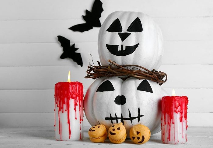 White Halloween pumpkins, candles and candies, on color wooden background