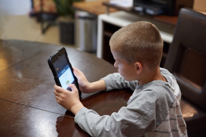 Boy using tablet indoors to learn. 