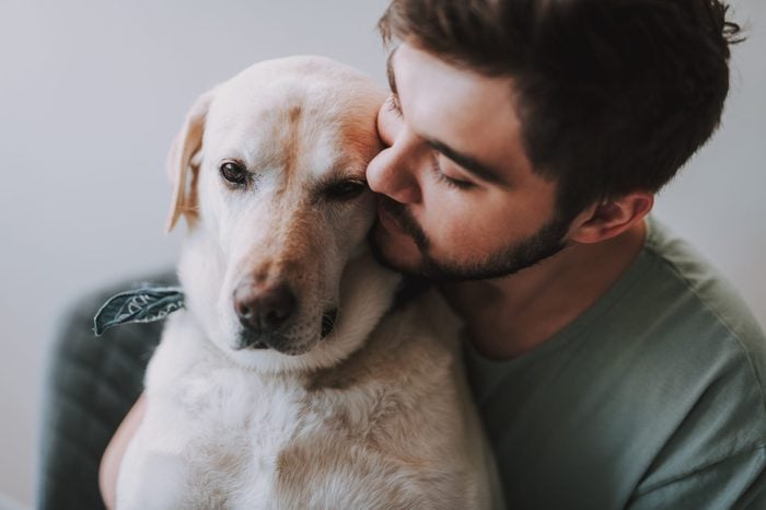 Close up of a bearded man kissing his dog while enjoying rest together
