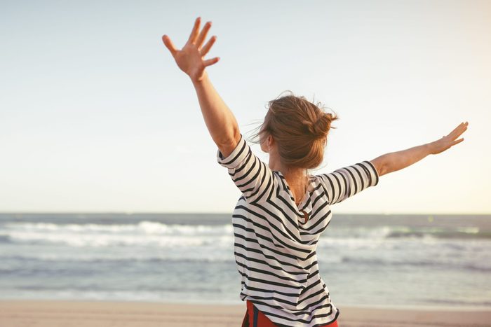 happy young woman enjoying freedom with open hands on sea