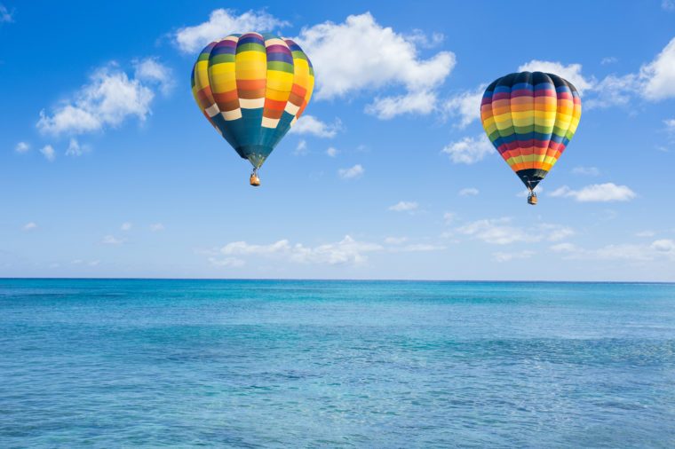 Horkovzdušný balón nad oceánom a mraky modrej oblohy