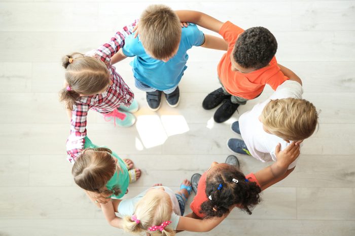 Little children making circle with hands around each other indoors, top view. Unity concept
