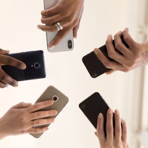 Male and female diverse hands holding cell phones, multiracial business people using smartphones applications software, users and devices concept, mobile communication, close up below bottom view