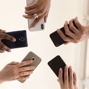Male and female diverse hands holding cell phones, multiracial business people using smartphones applications software, users and devices concept, mobile communication, close up below bottom view