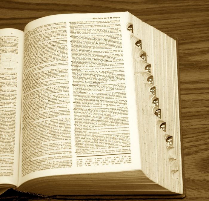 old dictionary with page open, showing side tabs on desk in sepia