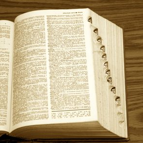 old dictionary with page open, showing side tabs on desk in sepia