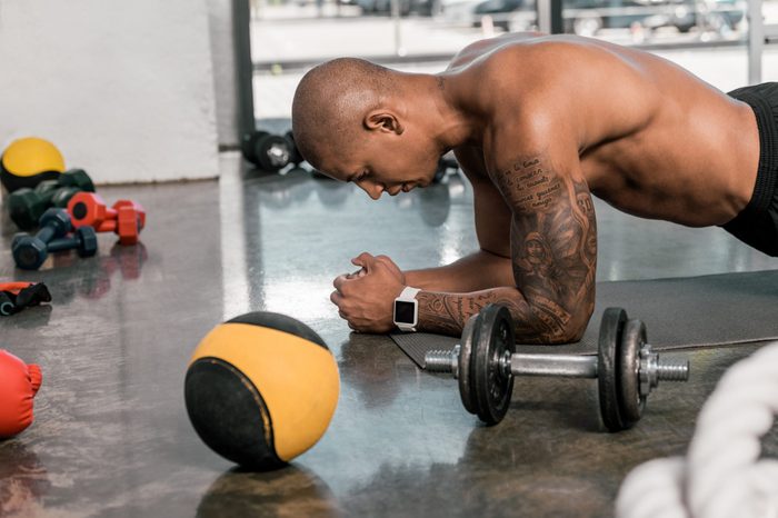 side view of muscular african american man doing push ups in gym