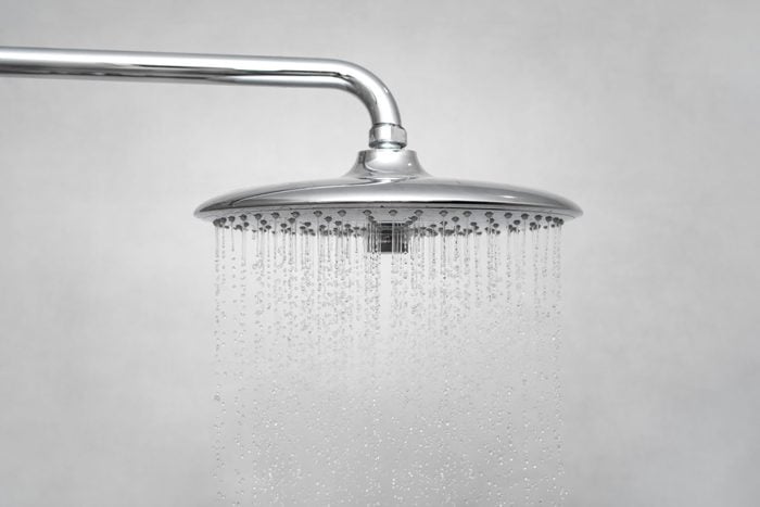 Water running from shower head and faucet in modern bathroom. Rain Shower turned, ceiling shower head closeup in the shower stall. 